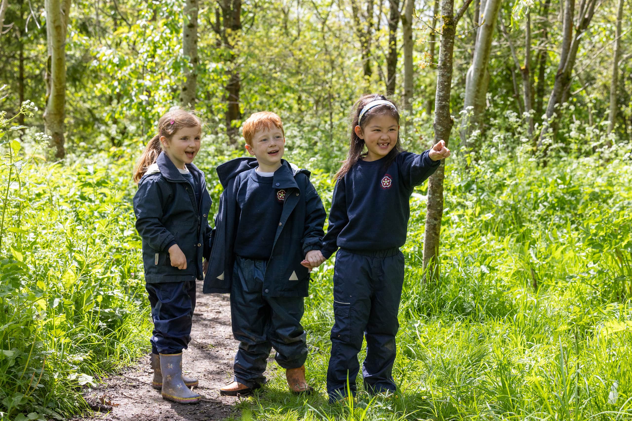 Three KES Bath pre-prep pupils standing in a forest