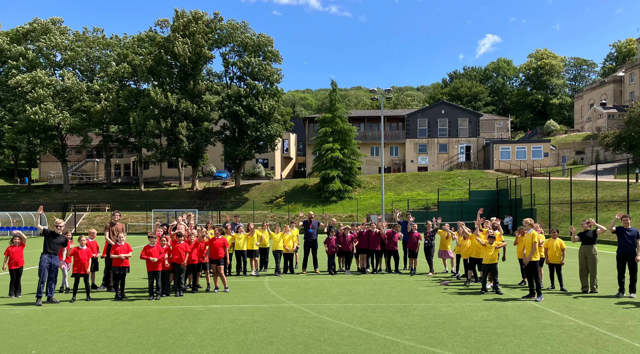 Group of young pupils standing in tennis courts with teachers